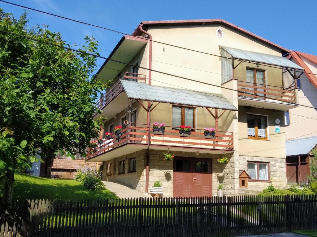 a house with a balcony with flowers on it at Kwatera u Somsiada -Apartament in Muszyna