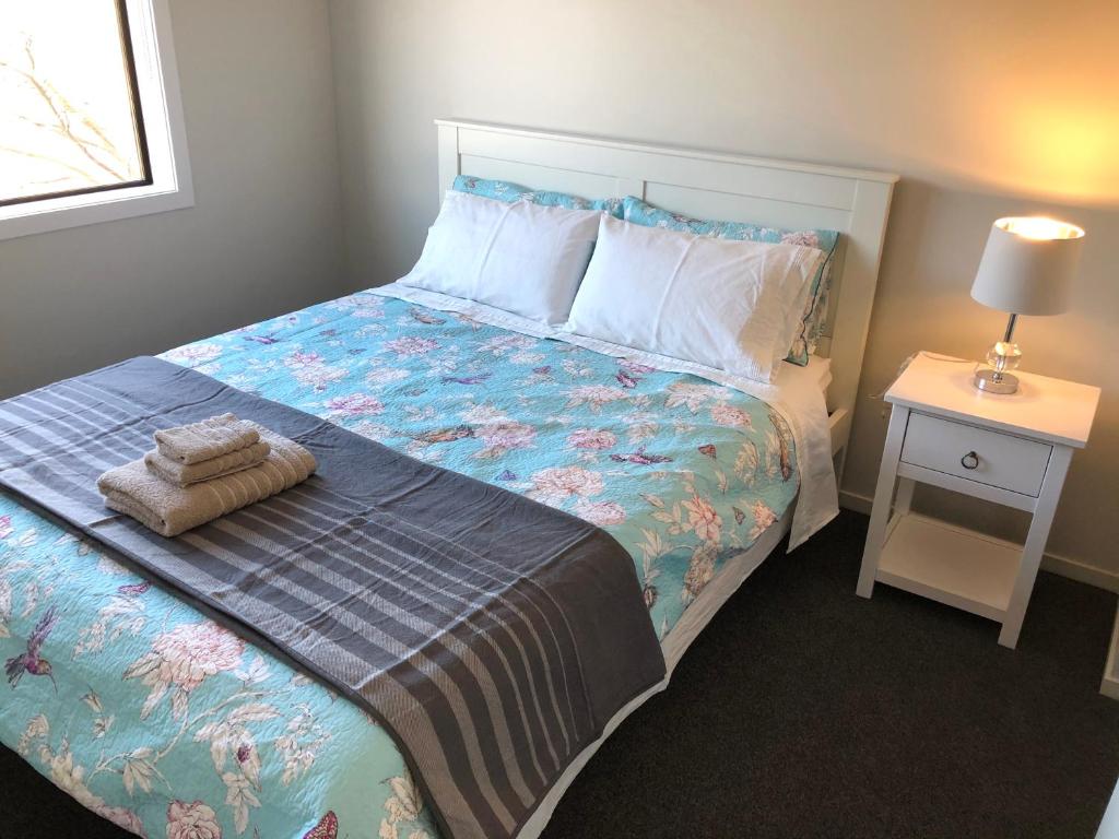 um quarto com uma cama e uma mesa de cabeceira com uma cama sidx sidx em Central Stadium Apartments em Hamilton