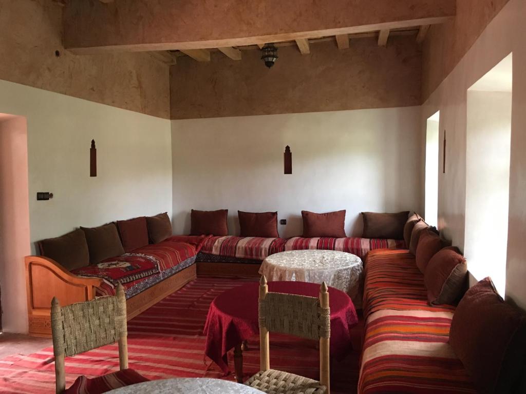a living room with a couch and a table and chairs at Maison D'hôtes Dar Afra in Aït Ziri