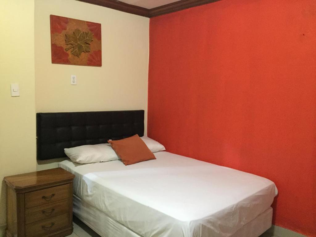 1 dormitorio con 2 camas y pared roja en Hotel Fika Guayaquil en Guayaquil