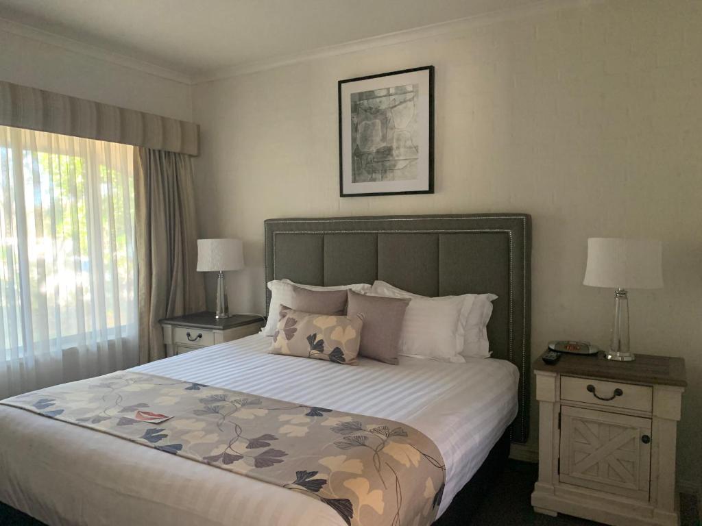 a bedroom with a large bed and a large window at Blazing Stump Motel & Suites in Wodonga