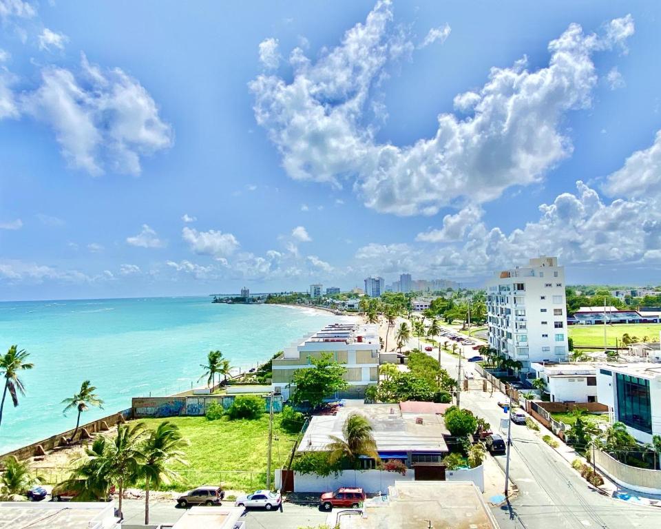 a view of a beach with palm trees and the ocean at KASA Starfish by the Sea - 8th floor Studio Apt for 2 BALCONY Ocean City View in San Juan