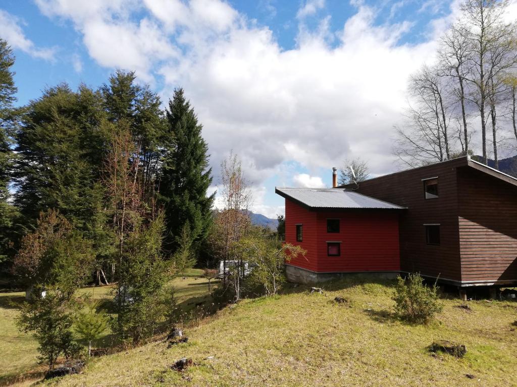 una casa roja en una colina en un campo en Cabaña en Caburgua, Pucon, en Pucón