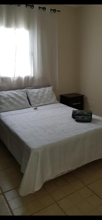 a bedroom with a white bed with a window at Casa da Cachoeira in Brotas