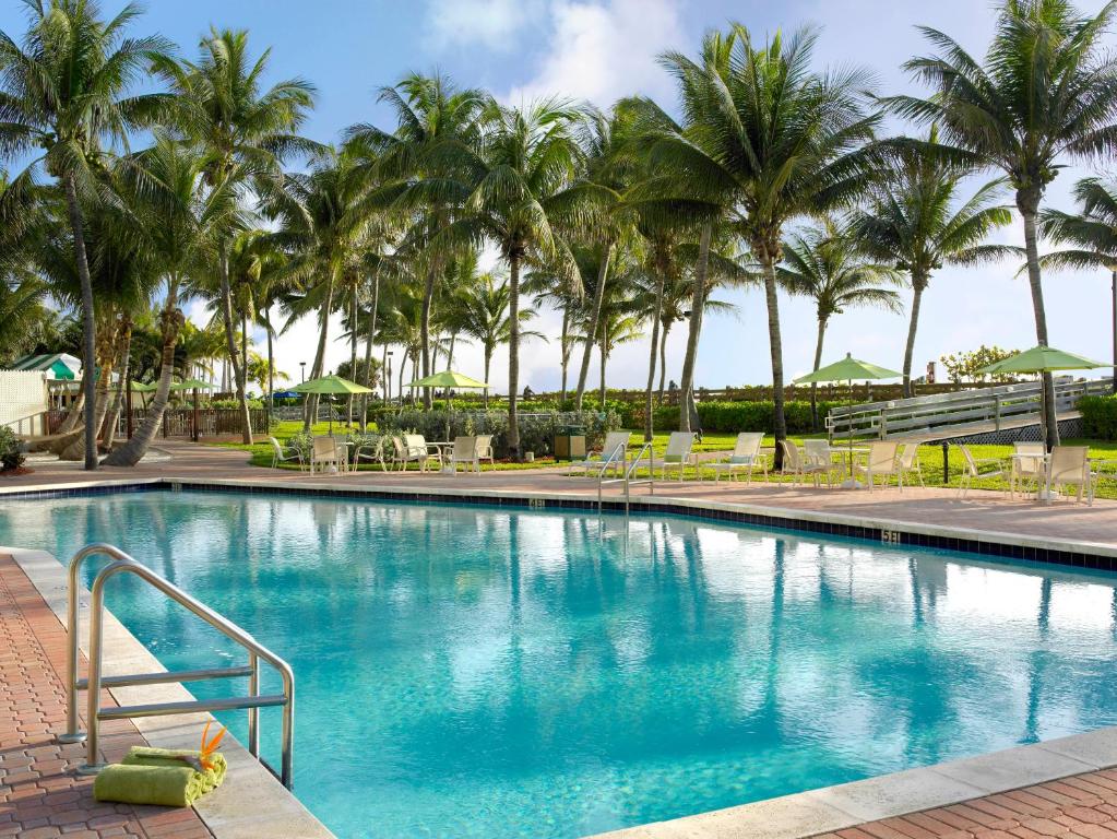 ein Pool mit Palmen im Hintergrund in der Unterkunft Holiday Inn Miami Beach-Oceanfront, an IHG Hotel in Miami Beach