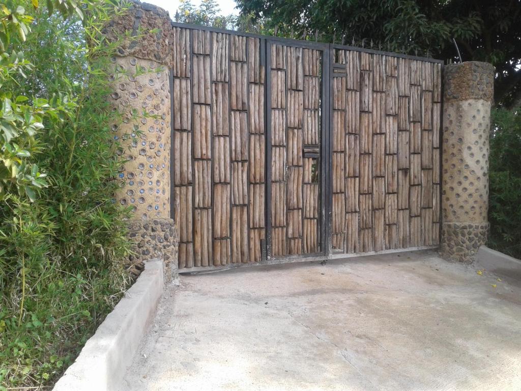 ein Holzzaun mit einem Tor darüber in der Unterkunft Plastic Bottles House in Entebbe