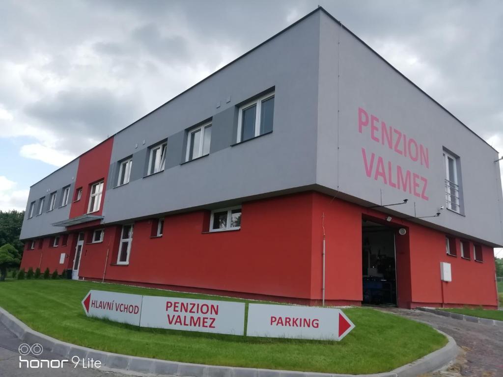 a red and white building with a parking garage at Penzion ValMez in Valašské Meziříčí