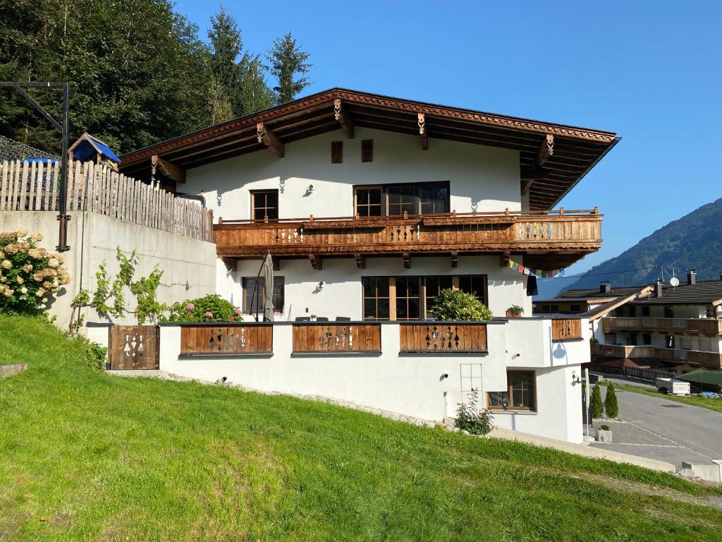 ein weißes Haus mit Holzbalkonen auf einem Hügel in der Unterkunft Ferienwohnung Gruber-Hansen in Kaltenbach