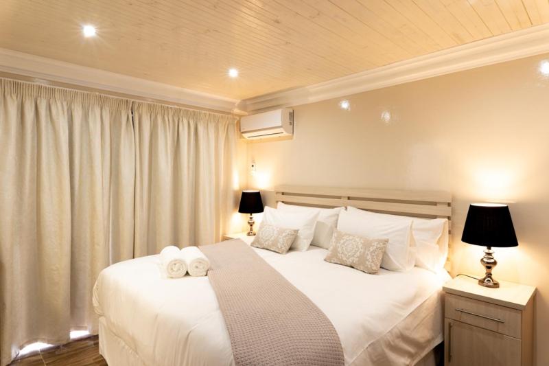 a bedroom with a white bed with two towels on it at Grand House Lodge And SPA Jeffreys Bay in Jeffreys Bay