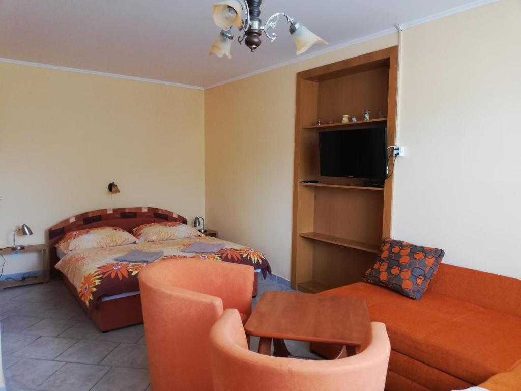 ein Schlafzimmer mit einem Bett, einem Sofa und einem Stuhl in der Unterkunft Ubytovanie Betty in Krásnohorské Podhradie