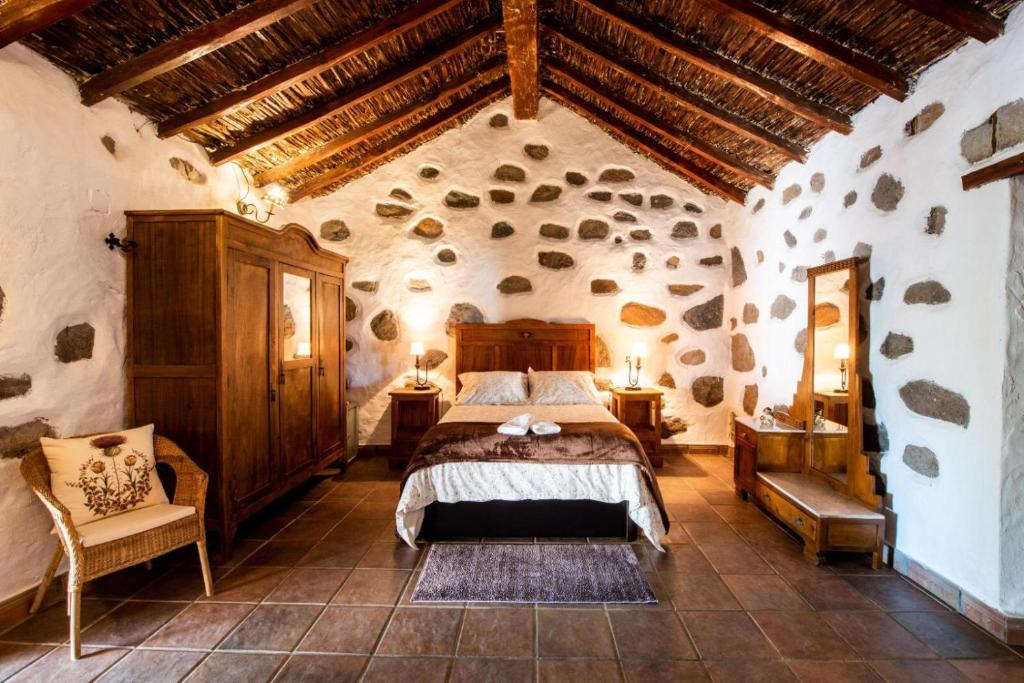 1 dormitorio con 1 cama grande en una habitación de piedra en Vv El Lagar de Tunte Fibra Internet, en San Bartolomé