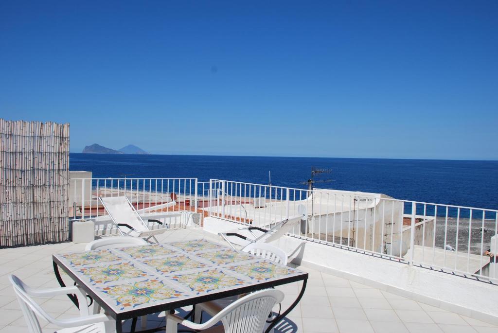 una mesa y sillas en un balcón con vistas al océano en Vulcanoconsult Appartamenti Spiaggia, en Lipari