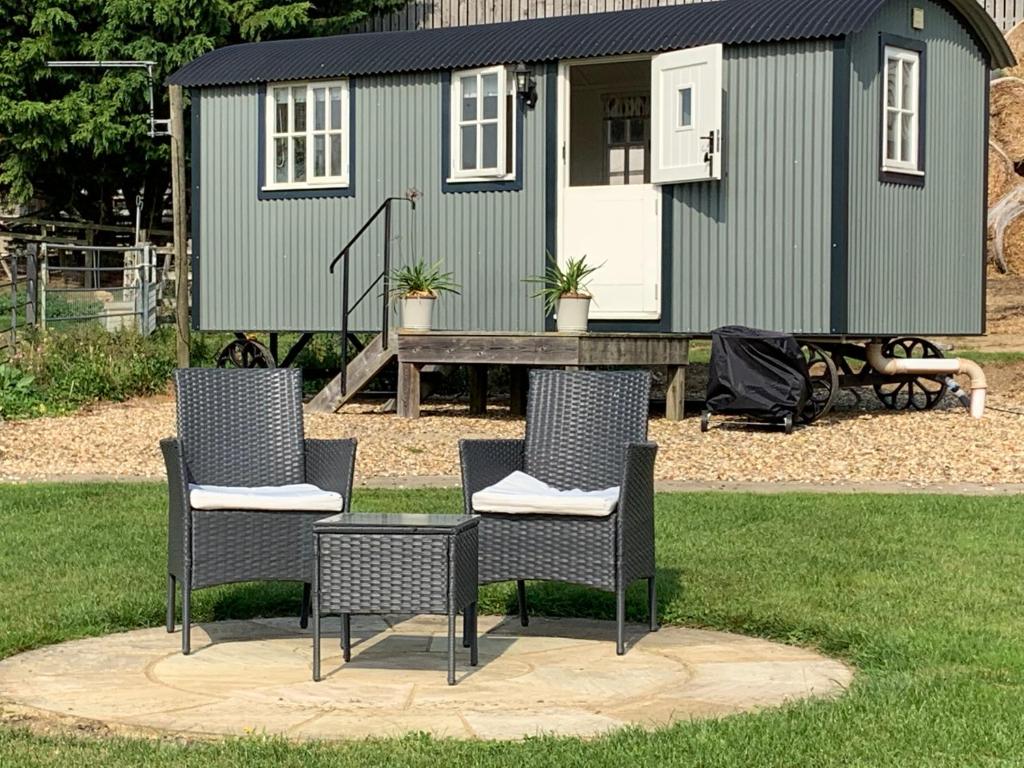 a group of chairs sitting in front of a tiny house at Weatherhead Farm Shepherds Hut in Buckingham