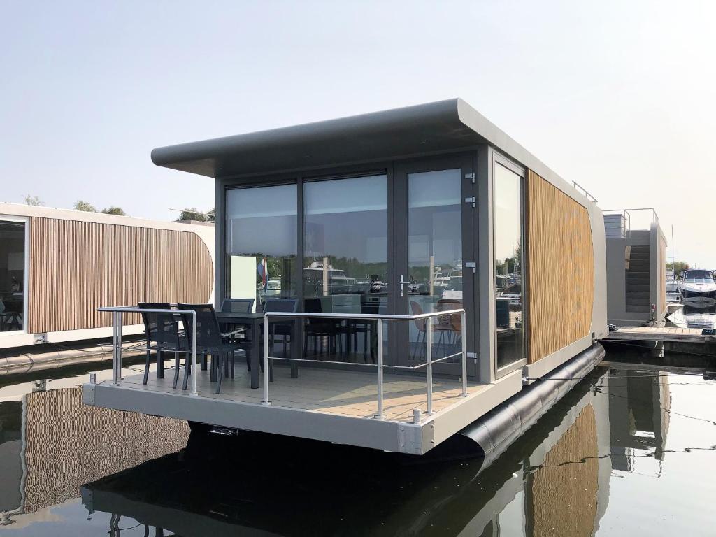 a house on a dock with a table on the water at Floating vacationhome Tenerife in Maastricht