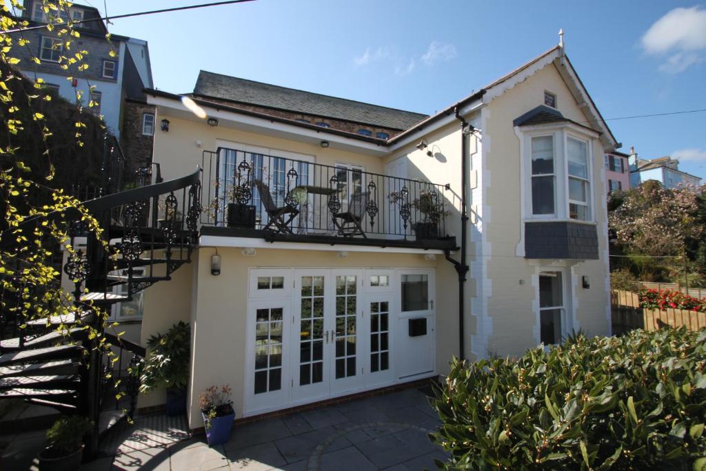 a white house with a balcony and a door at St Elmo House in Dartmouth