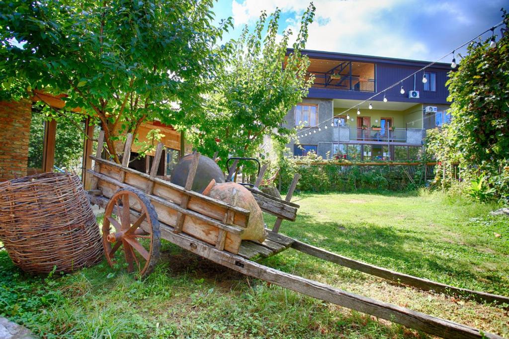 une charrette en bois assise dans l'herbe devant une maison dans l'établissement Bucha`s Guest House & Wine Cellar, à Telavi