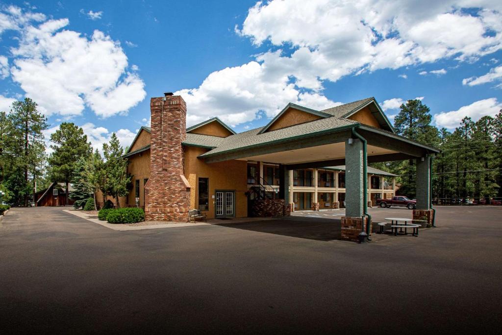 a large house with a brick chimney in a parking lot at Quality Inn Pinetop Lakeside in Pinetop-Lakeside