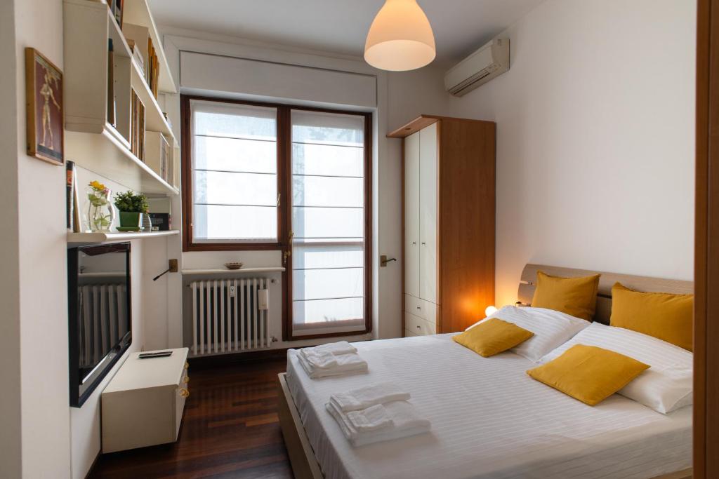 ein Schlafzimmer mit einem großen weißen Bett mit gelben Kissen in der Unterkunft MilanoView Apartment in Mailand
