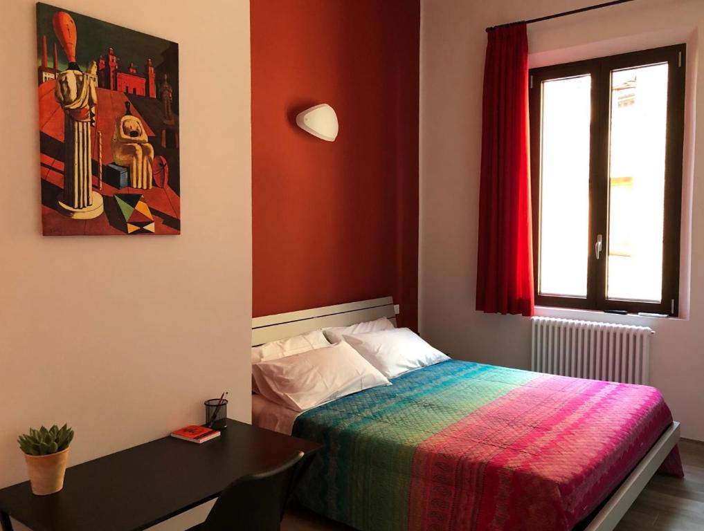a bedroom with a bed and a table and a window at Triquetra - Rooms for Rent in Ferrara