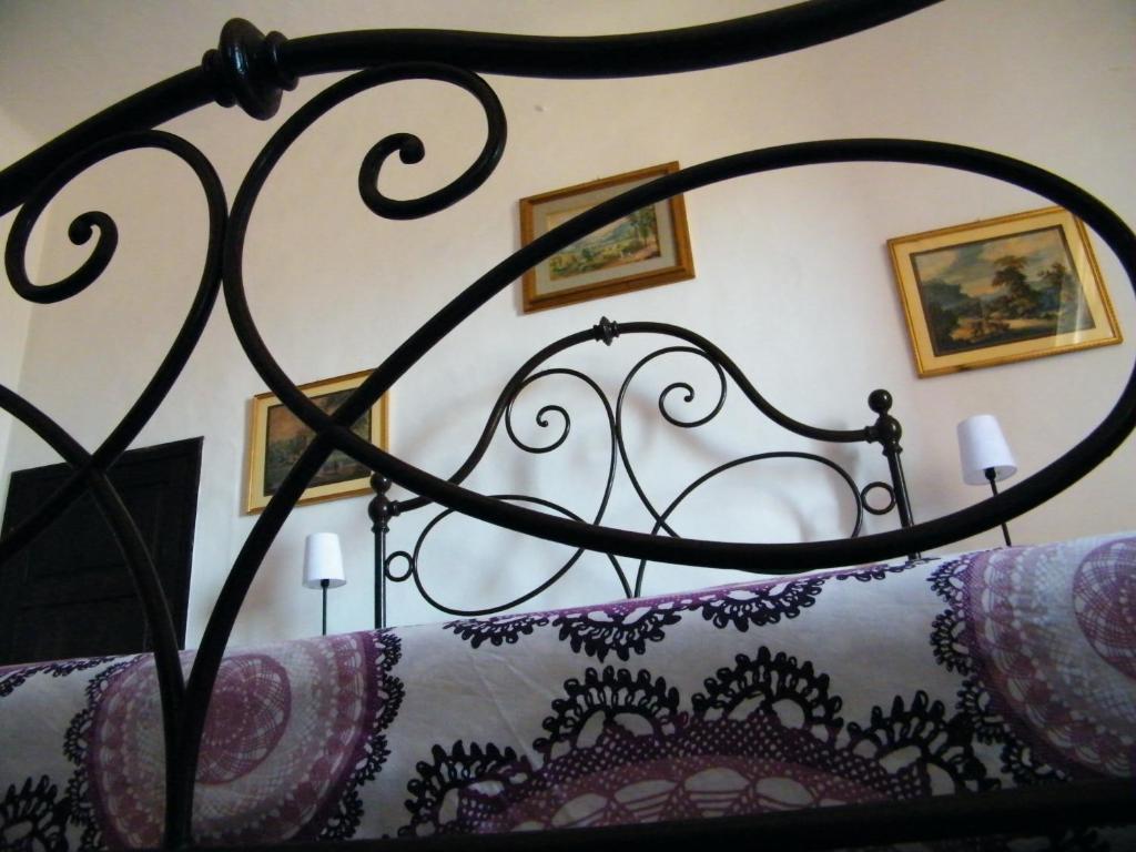 a bed with a black iron headboard and pictures on the wall at B&B Il Glicine in Montefollonico
