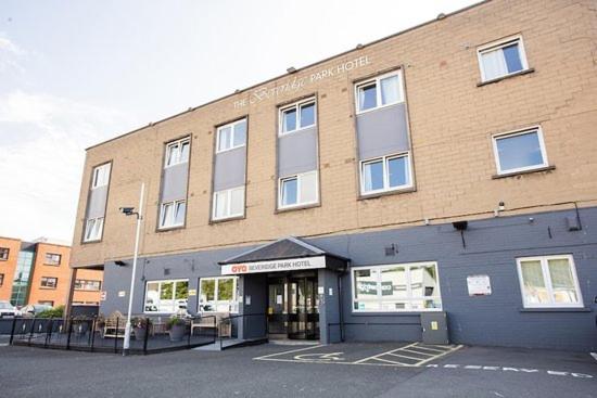 a large brick building with a parking lot in front of it at Beveridge Park Hotel in Kirkcaldy