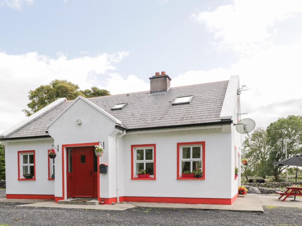 ein weißes und rotes Haus mit einer roten Tür in der Unterkunft Lough Mask Road Fishing Cottage in Cong