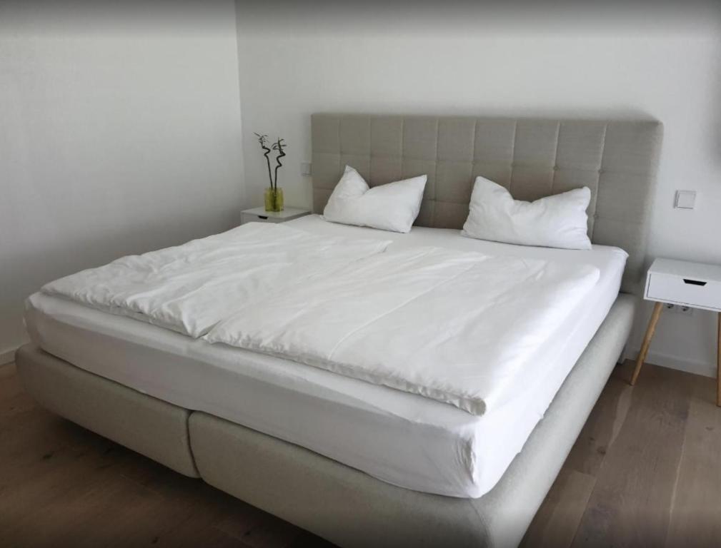 un grande letto bianco con lenzuola e cuscini bianchi di Glanzvoller - Deine Auszeit a Markdorf