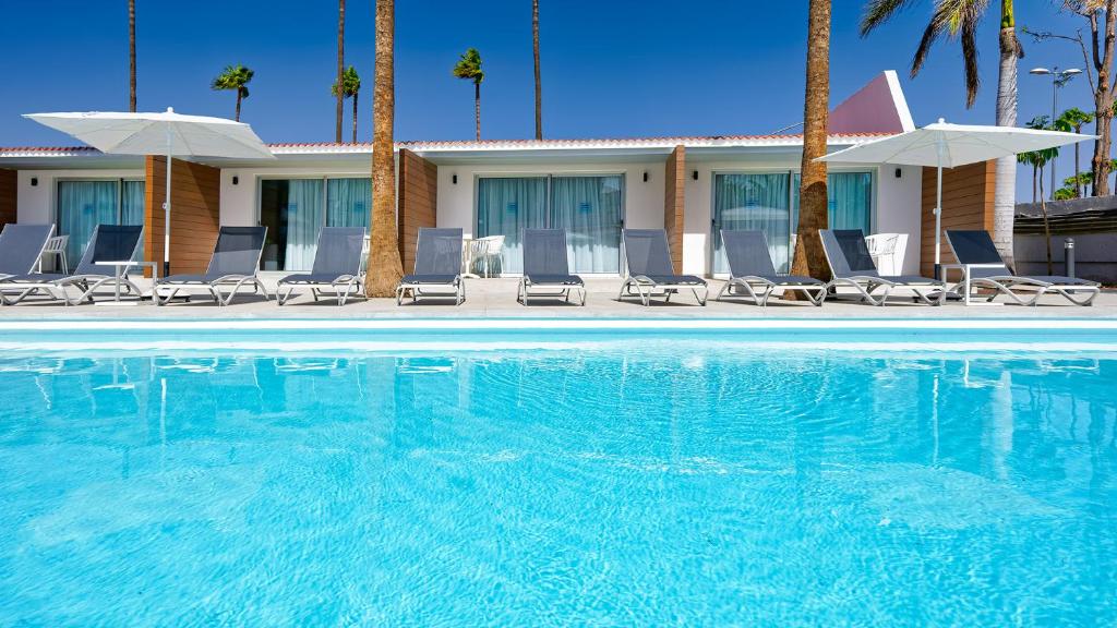 uma piscina num hotel com cadeiras e palmeiras em Sanom Beach Resort Only Adults em Playa del Inglés