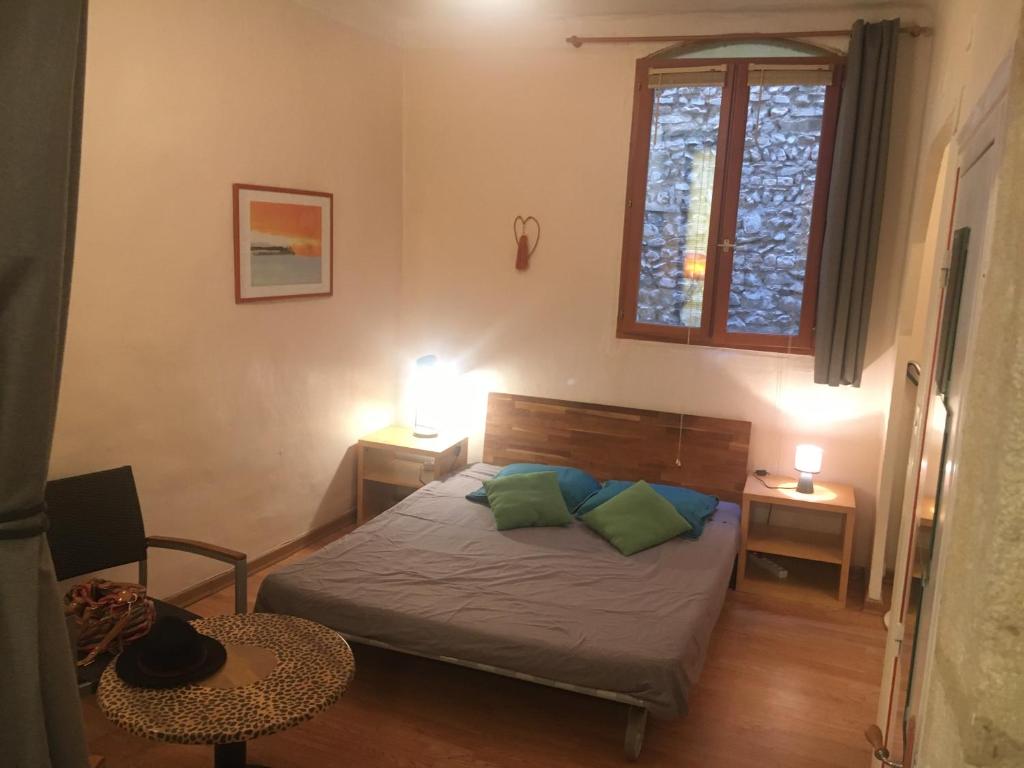 um pequeno quarto com uma cama e uma janela em Appart sympa dans le vieux Nimes em Nîmes