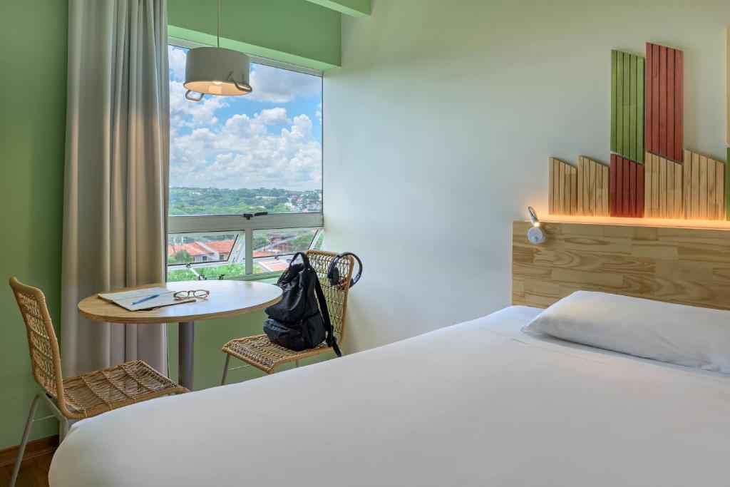 a room with a bed and a table and a window at Hotel Nacional Inn Curitiba Santa Felicidade in Curitiba