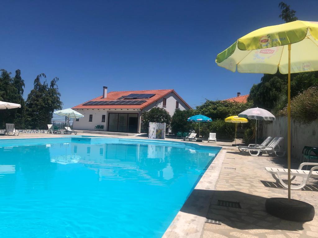 uma grande piscina com guarda-sol e cadeiras em Quinta das Cegonhas em Gouveia
