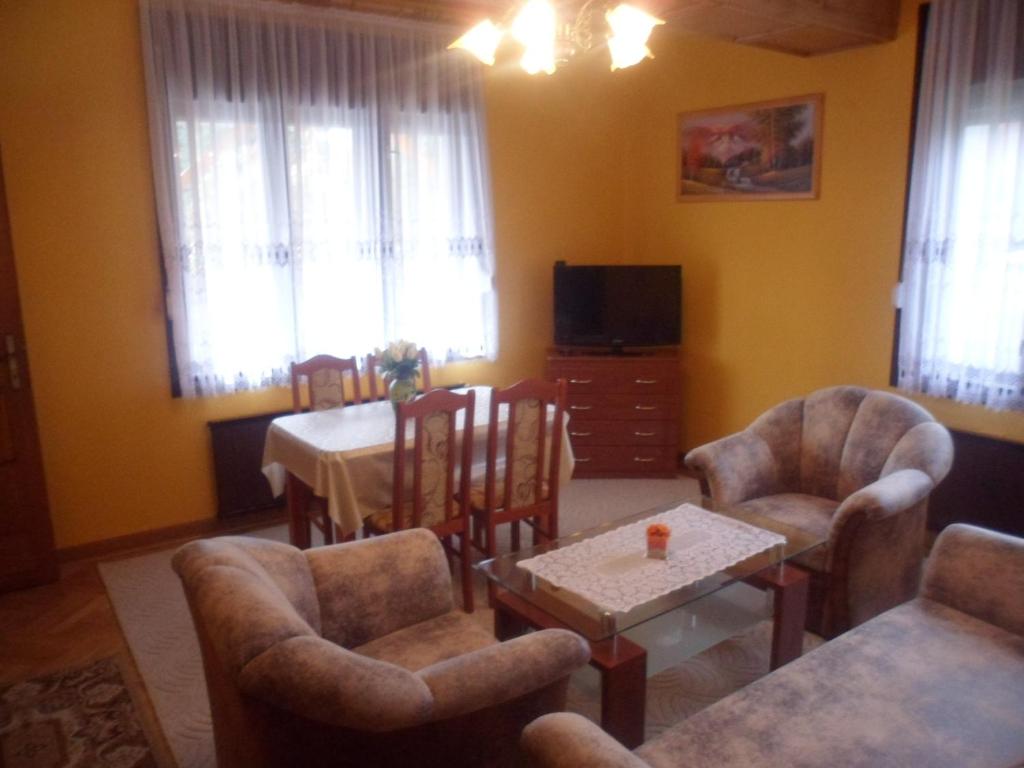 ein Wohnzimmer mit Stühlen, einem Tisch und einem TV in der Unterkunft Liget Vendégház in Zalakaros