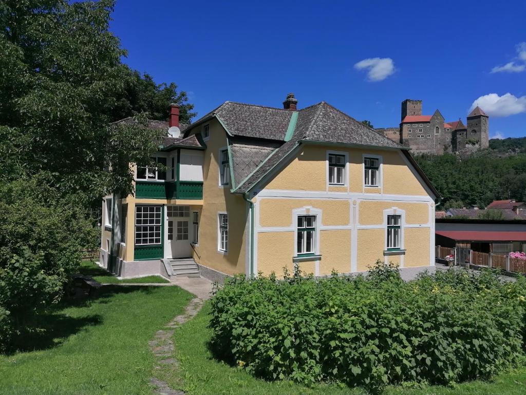 a large yellow house with a castle in the background at Villa Hardegg in Hardegg