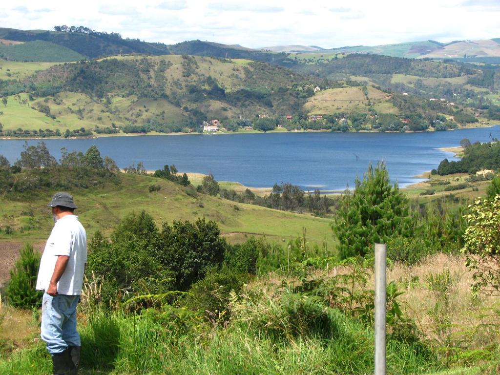 a man standing on a hill looking at a lake at El Cobijo in Chocontá