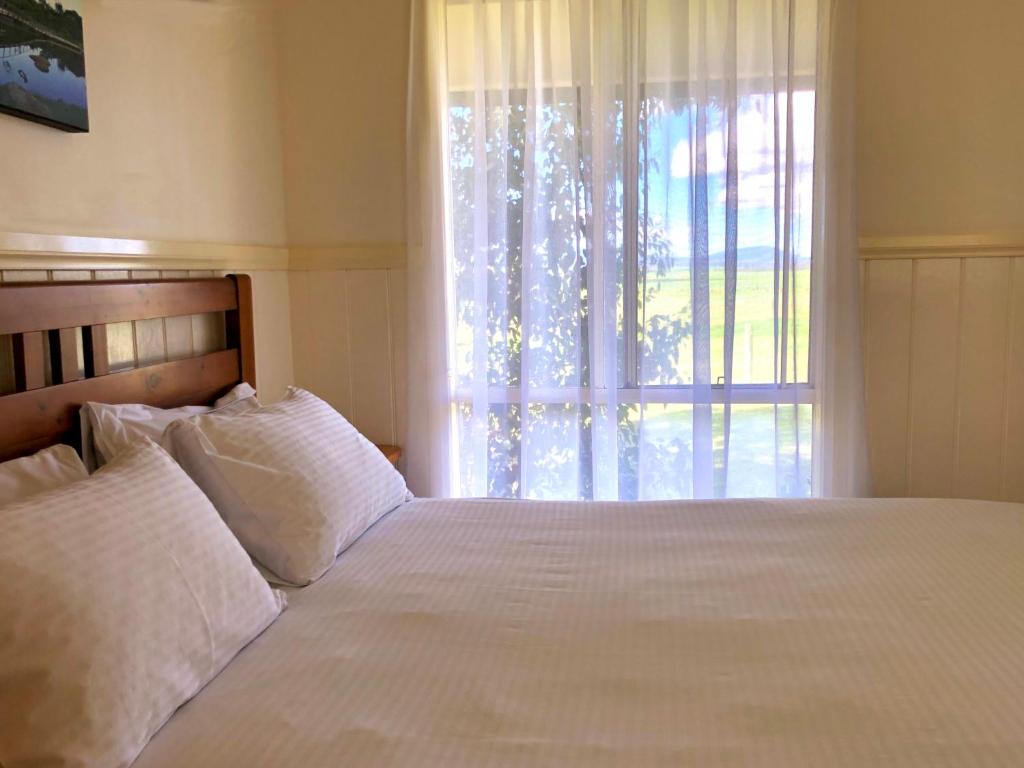 a bedroom with a large white bed with a window at Promhills Cabins in Yanakie