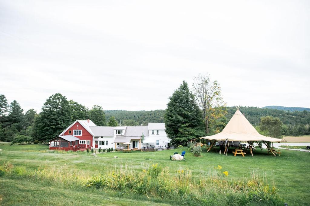 a large field with a tent and a house at Craftsbury Farmhouse in Craftsbury