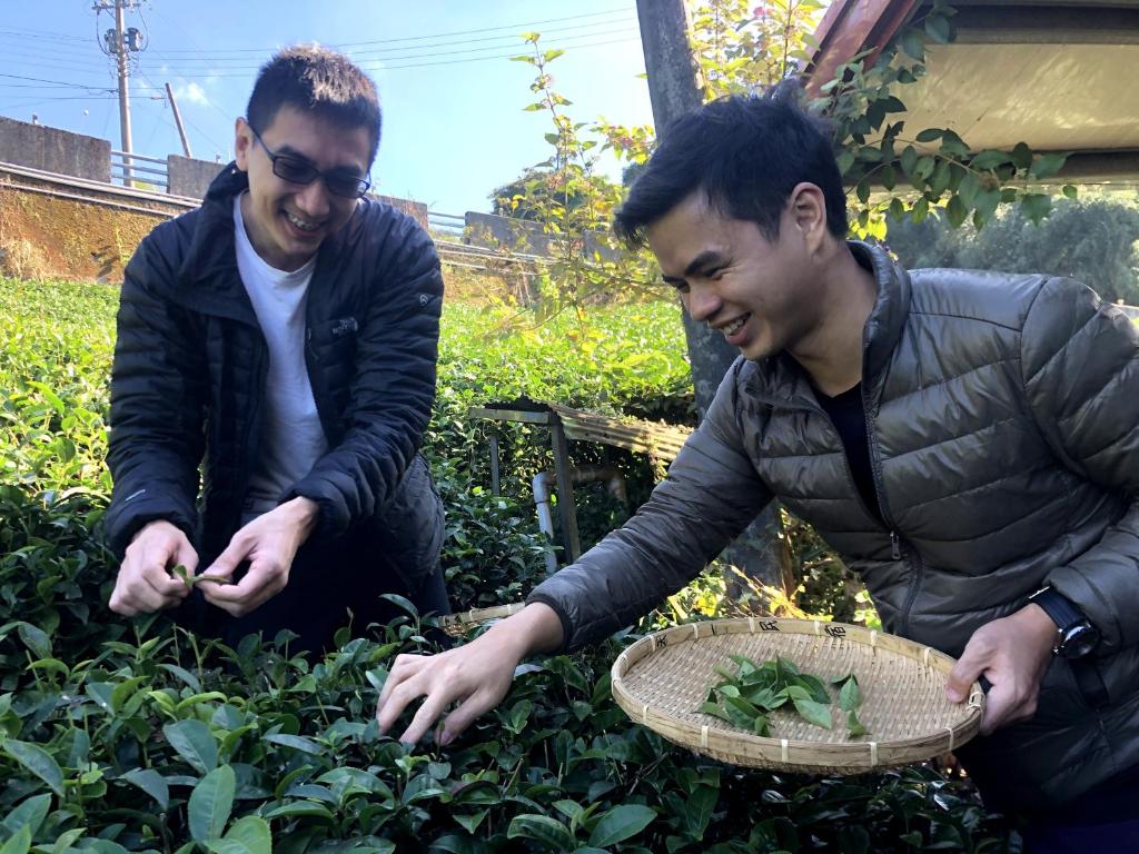 two men are looking at plants in a garden at Tianyi Homestay in Fenqihu
