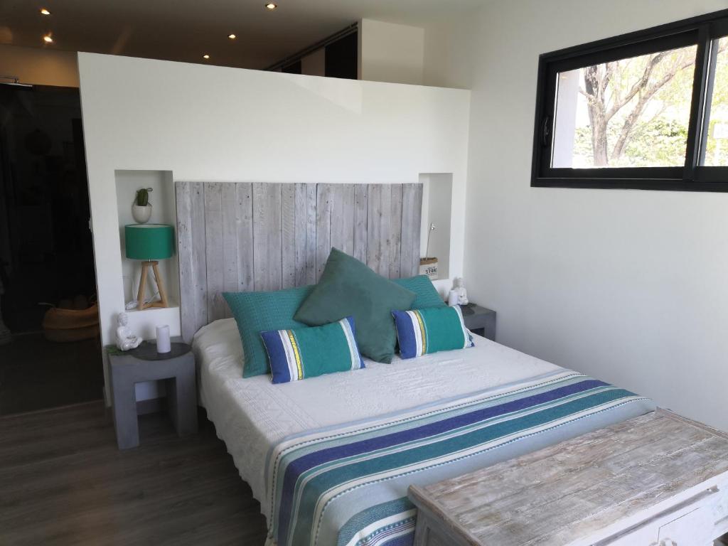 Un dormitorio con una cama con almohadas azules y una ventana en Chez Jeff & Aurélie, en Draguignan
