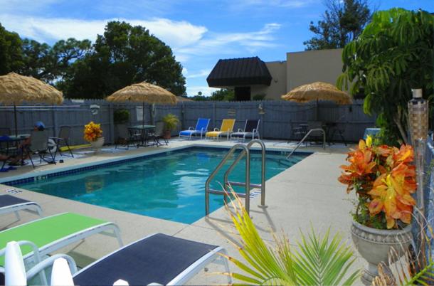 a swimming pool with chairs and umbrellas at Island Breeze Inn - Venice in Venice