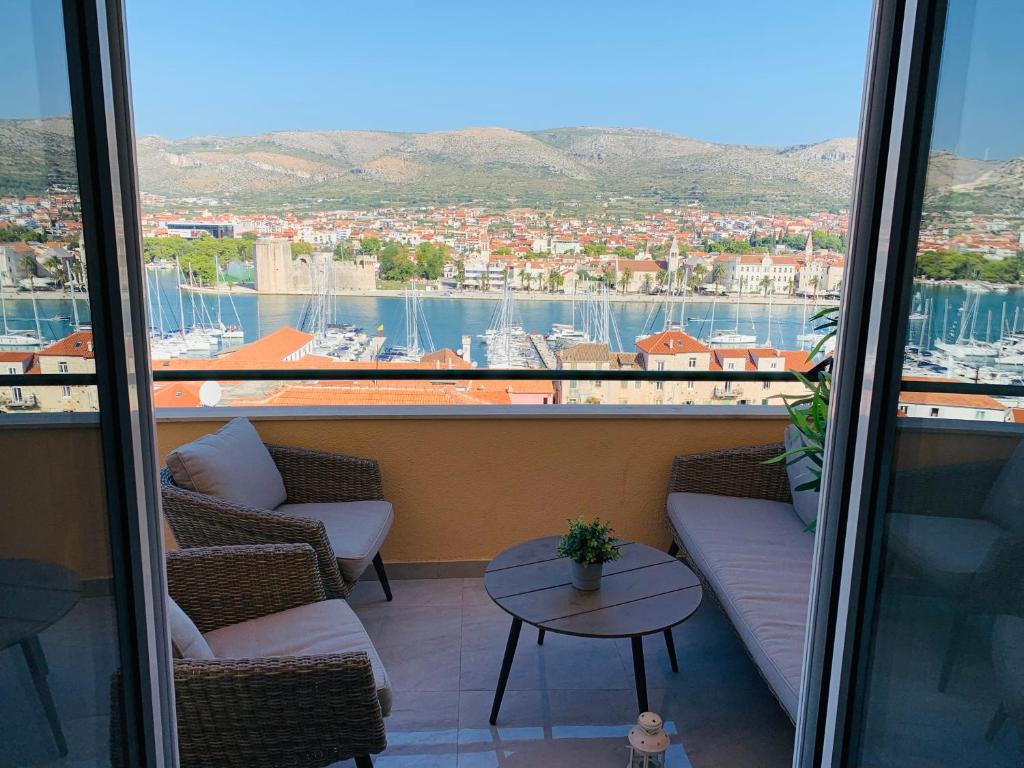 a balcony with chairs and a table and a view of a harbor at Mentha Apartments Trogir in Trogir