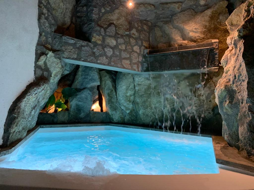 una piscina en una cueva con cascada en Rock House Villa, en Isquia