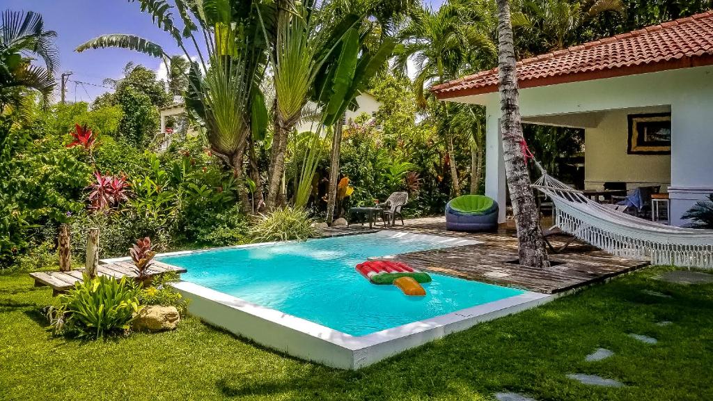 a swimming pool with a hammock in a backyard at Villa Strelitzia Cabarete in Cabarete