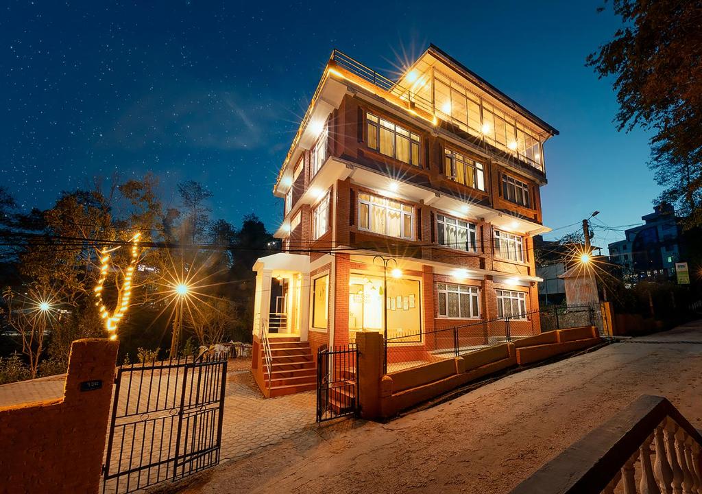 a large wooden house with lights on it at night at Asha Lodges in Dhulikhel