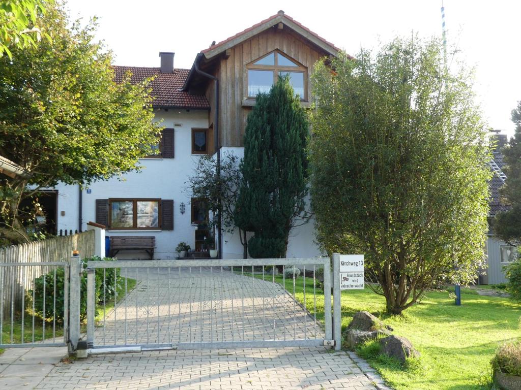 una casa blanca con una valla delante en Ferienwohnung Bergblick en Hohenpeißenberg