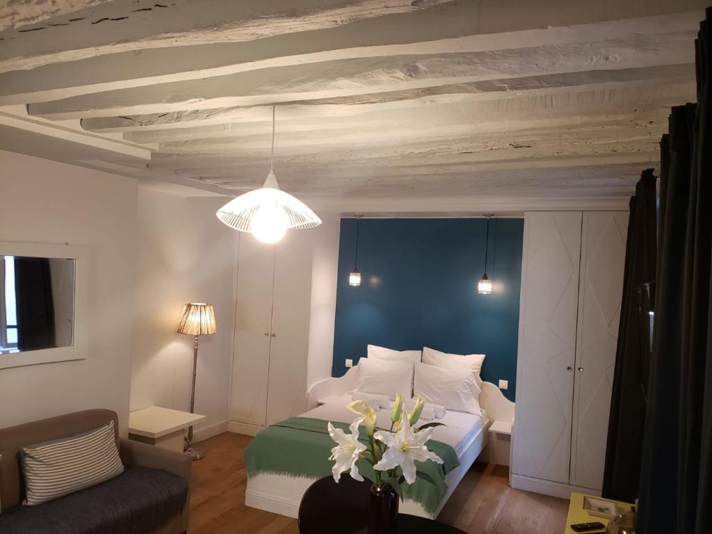 - une chambre dotée d'un lit avec des draps blancs et des fleurs dans l'établissement LOUVRE ST GERMAIN Rue VERNEUIL, à Paris