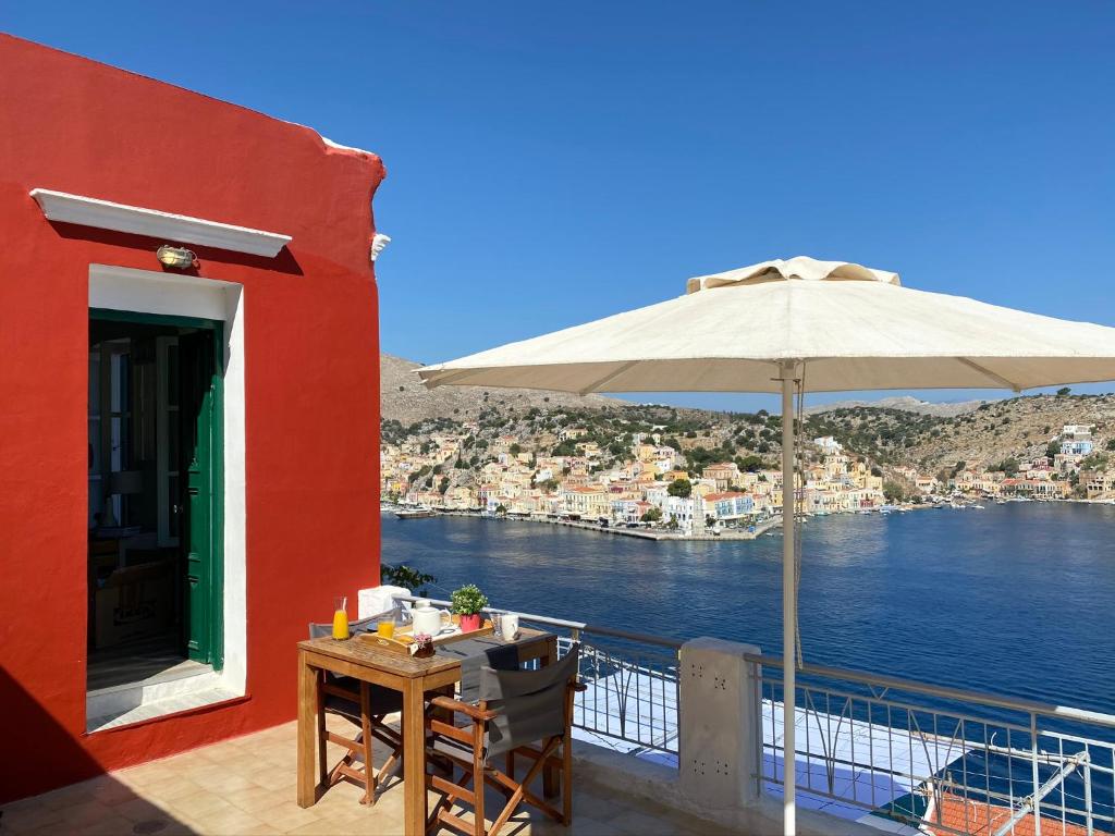 eine Terrasse mit einem Tisch und einem Sonnenschirm auf dem Balkon in der Unterkunft Thodoris Infinity View Apartments in Symi