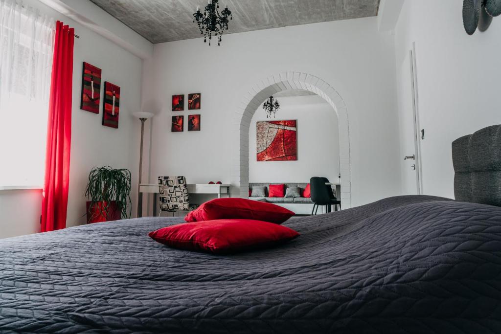 a bedroom with a bed with red pillows on it at Lora & Lana Resort in Ljubljana