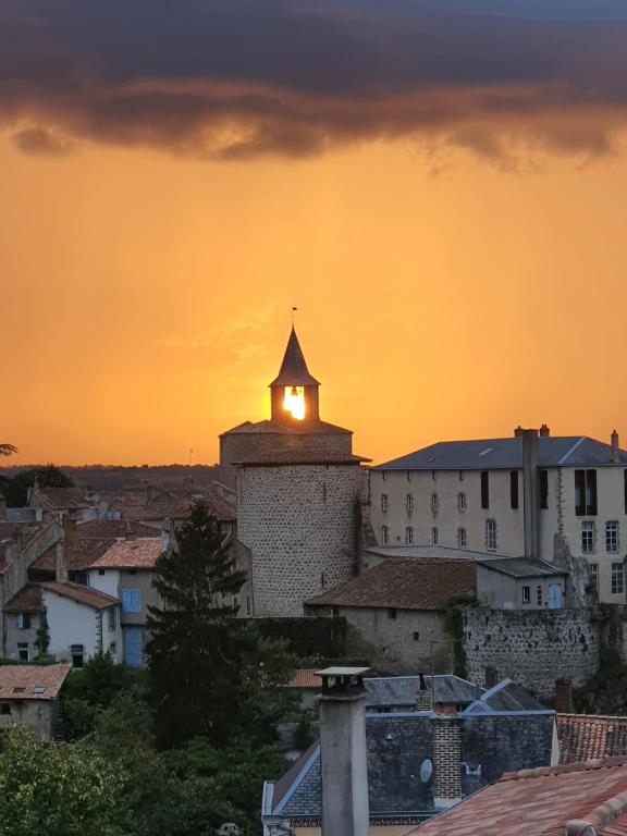 a building with a clock tower with a sunset in the background at LES 5 ESCALES in Parthenay