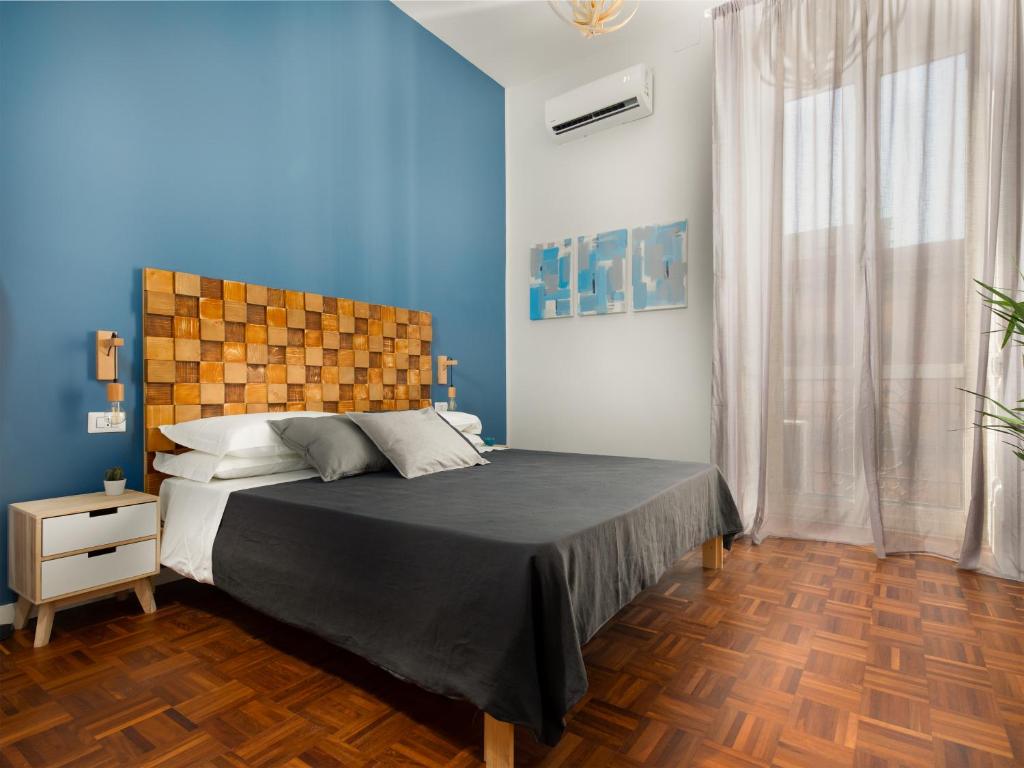 um quarto com uma cama grande e paredes azuis em Nartè Rooms em Nápoles