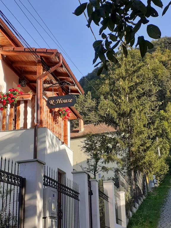 une maison blanche dotée d'une clôture et d'un panneau. dans l'établissement R-House, à Braşov